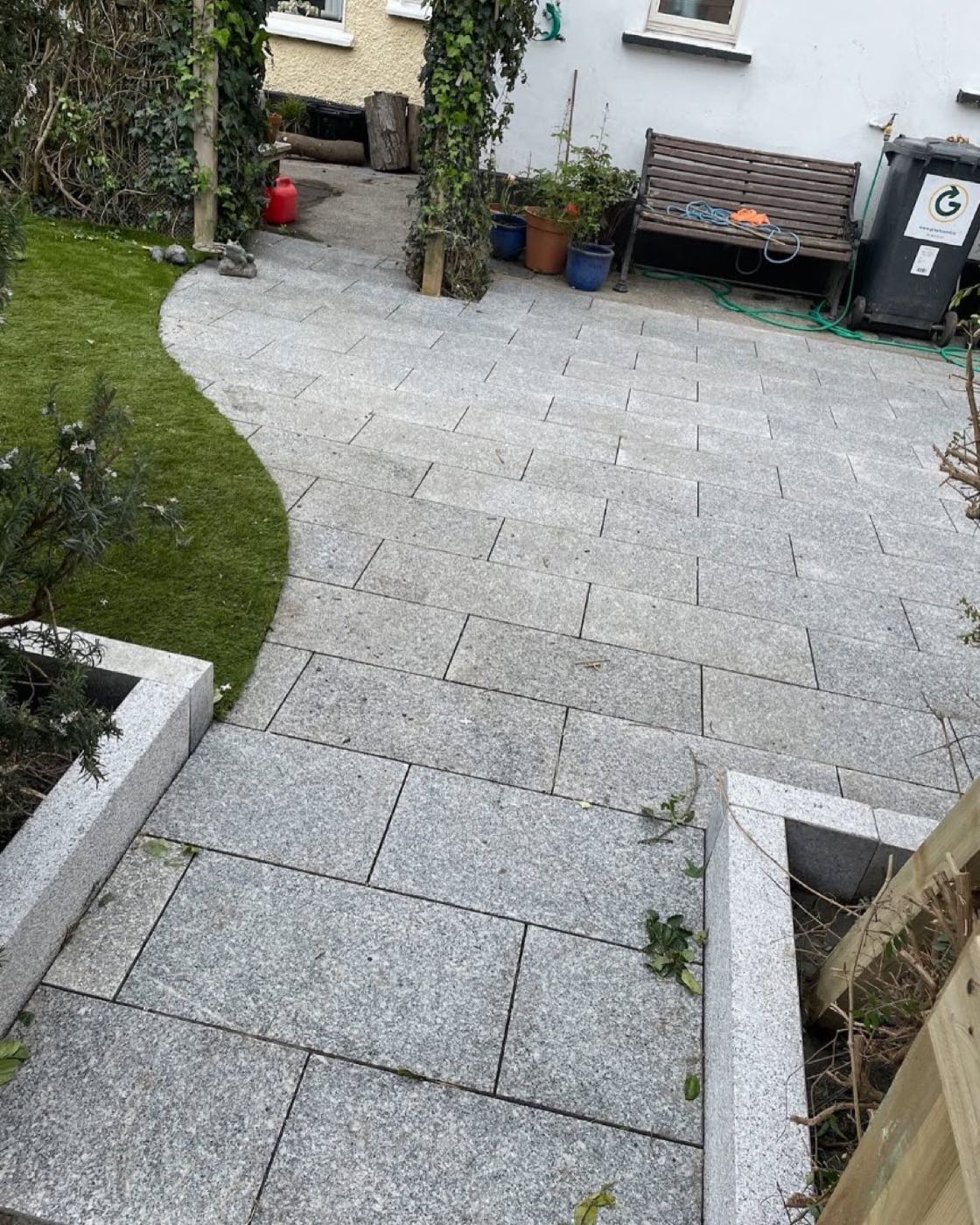 Curved silver granite paving path wrapping around a lawn in a narrow Dublin garden